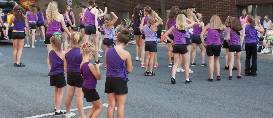 Younger members of the dance troop stand back and watch as the older participants go through with their routine.