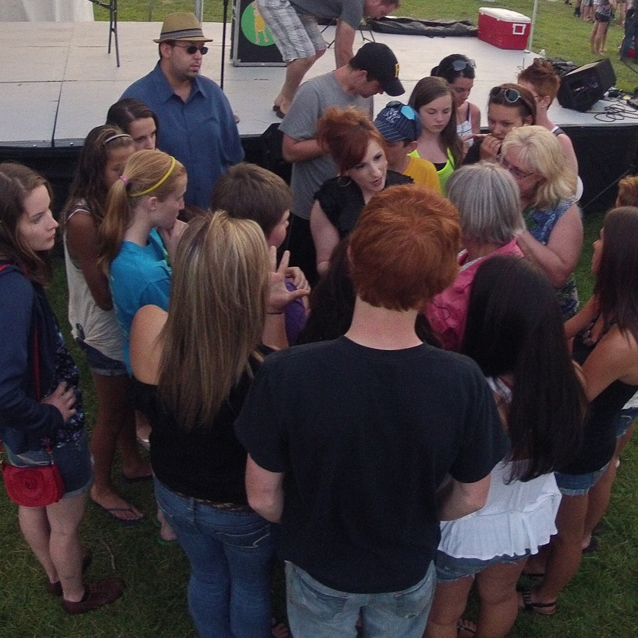 Raven reads a volunteer's palm as a crowd surrounds them.