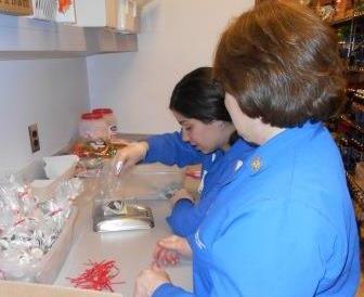 Cheryl Fleck (front) and Danielle Minori (back), UPMC Altoona volunteers, weigh and bag candy for the gift shop. (Provided photo)