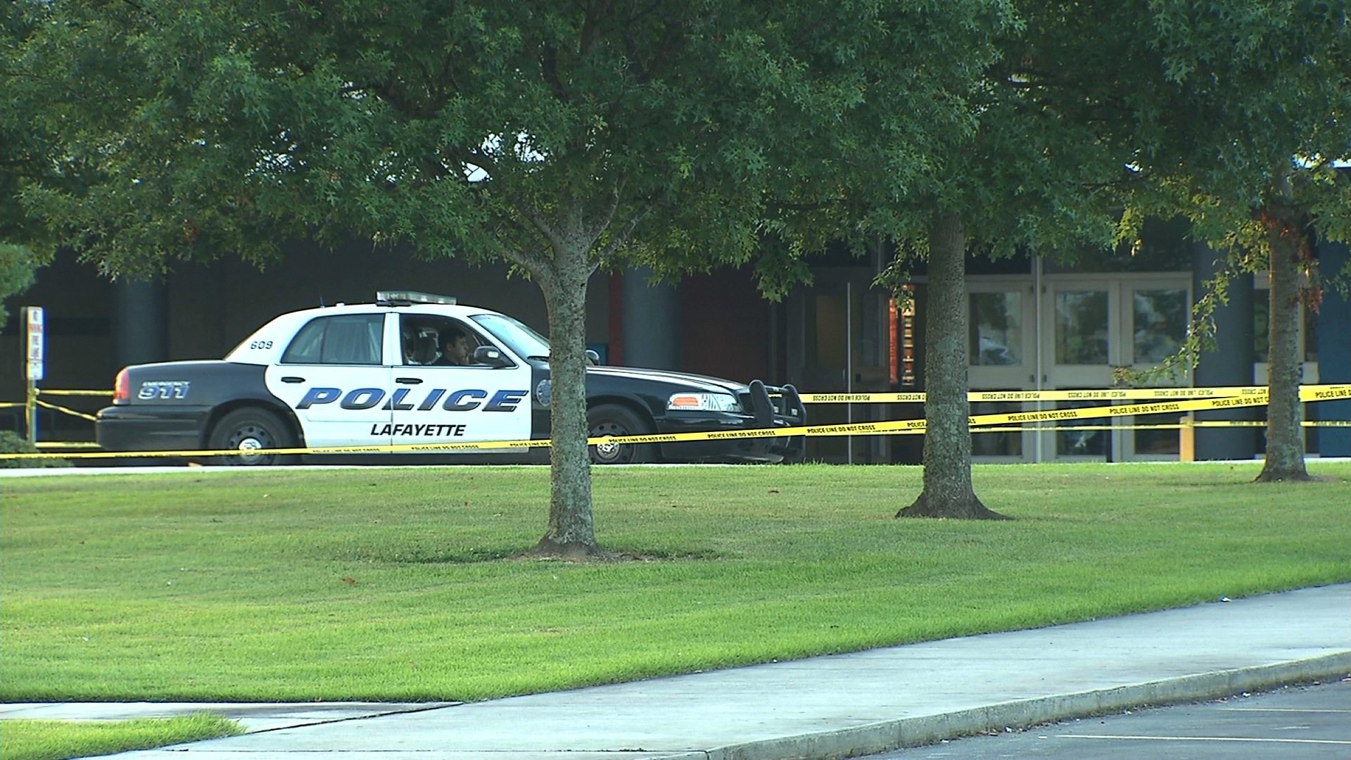 A police officer sits in his patrol car on the morning after a shooting at the Lafayette, Louisiana, Grand 16 movie theater. Three people died, including the gunman, and nine others were injured Thursday night, July 23, 2015, law enforcement said.