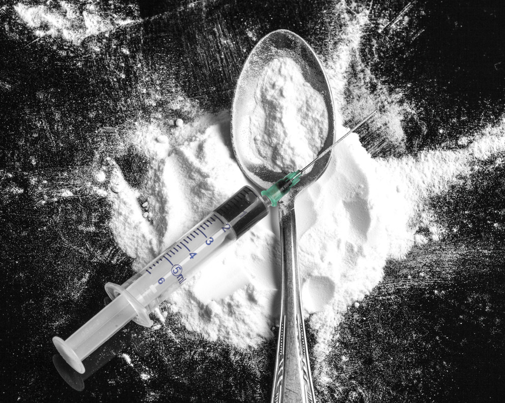 Drug syringe and cooked heroin on spoon. Studio shot