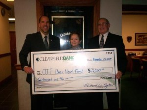 Michael J. Bibak, president of Clearfield Bank & Trust Co. (left), and Dennis Hampton, senior vice president and Trust Investment Division manager (right), present a check for $2,000 to Nancy Micks, board member of the Clearfield County Charitable Foundation (center), for the foundation’s Basic Needs Fund that makes annual donations to several local food banks. (Provided photo)