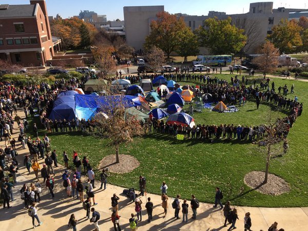 Students and faculty members form a circle around a campsite occupied by protesters at the University of Missouri.
