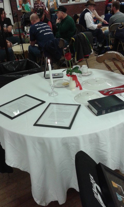 The POW/MIA table stands on display during the 16th annual Veteran's Day Pow Wow, held Saturday and Sunday at the Expo II building at the Clearfield Driving Park. The white tablecloth draped over the table represents the purity of their response to our country’s call to arms. The empty chair depicts an unknown face, representing no specific Soldier, Sailor, Airman, or Marine, but all who are not here with us. The table itself is round to show that our concern for them is never ending. The Bible represents faith in a higher power and the pledge to our country, founded as one nation under God. The napkin stands for the emptiness these warriors have left in the hearts of their families and friends. A Purple Heart medal can be pinned to the napkin. The single red rose reminds us of their families and loved ones. The red ribbon represents the love of our country, which inspired them to answer the nation’s call. The candle and its yellow ribbon symbolize the everlasting hope for a joyous reunion with those yet accounted for. The slices of lemon on the bread plate remind us of their bitter fate. The salt upon the bread plate represent the tears of their families. The wine glass, turned upside down, reminds us that our distinguished comrades cannot be with us to drink a toast or join in the festivities of the evening. (Photo by Kimberly Finnigan)