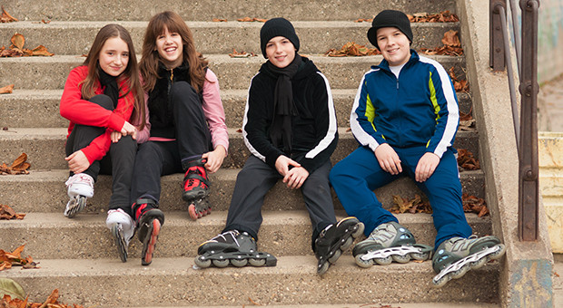 Happy teenagers sitting on stairs in roller skates