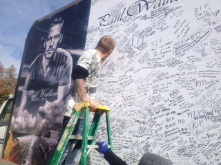 A Paul Walker fan signs a huge poster board on Sunday, December 8, 2013, paying tribute to the actor. It was part of a memorial for the fallen hero of the "Fast and Furious" movies.