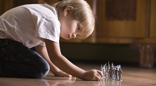 Boy playing with toy soldiers on floor