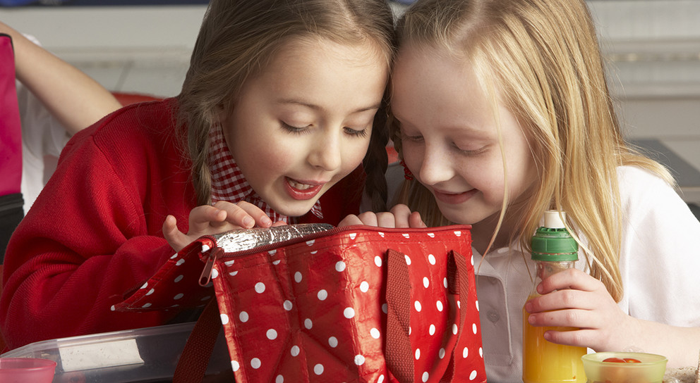 Primary School Pupils Enjoying Packed Lunch In Classroom