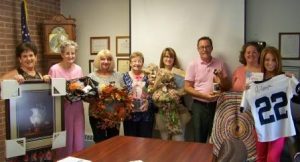 Some of this year’s committee members, (from left) Michele Fannin, Donna Shaw, Ellie Fenton, Joan Bracco, Ronda Vaughn, Kenn Starr, Valerie Darrow, and Erica Vezza, are showcasing just a few of the items up for bid at this year’s 21st annual Anne S. Thacik Charity Auction. (Provided photo)