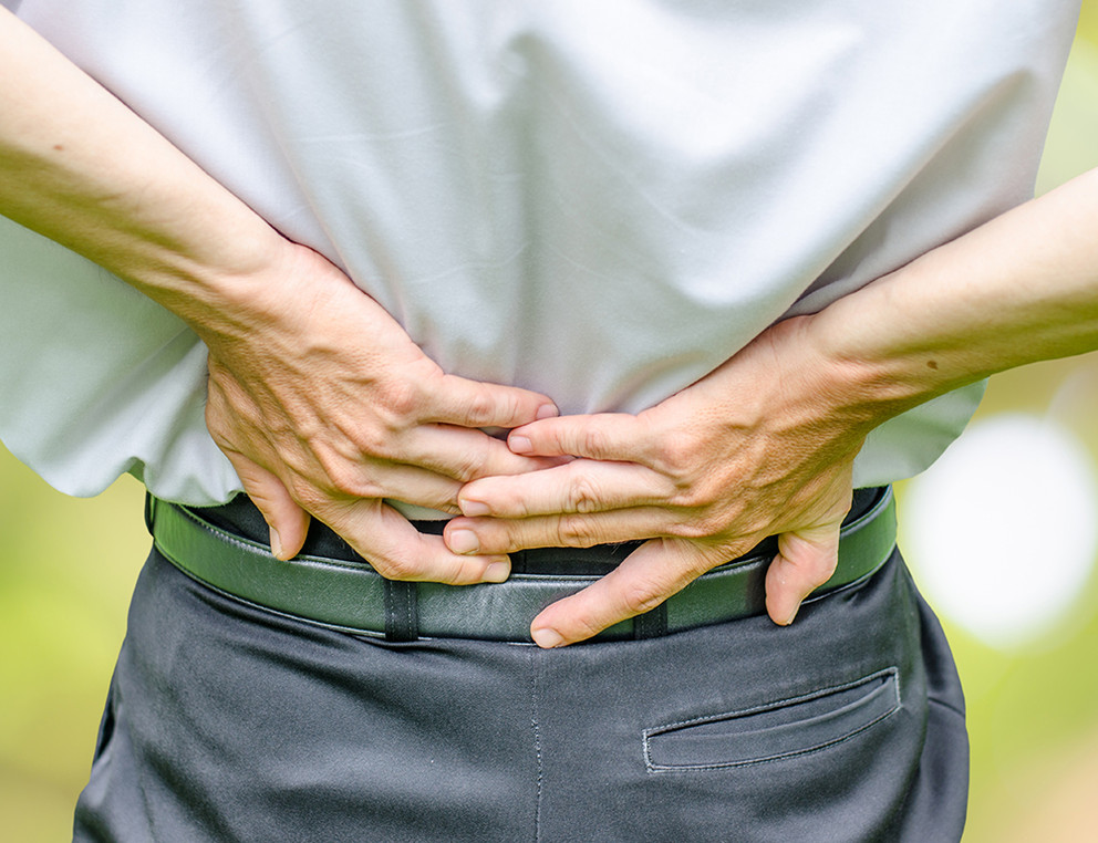 close up of a  man holding his back in pain, isolated on white background, monochrome photo with red as a symbol for the hardening