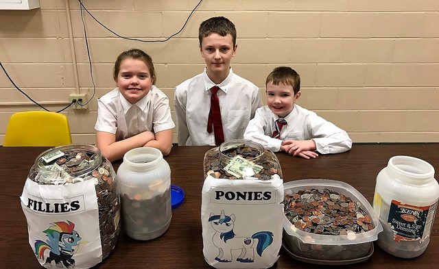 Pictured with the “coin war” collection from the final day are students Khloe Lanich, Karson Rumsky and Jacob Wright. (Provided photo)