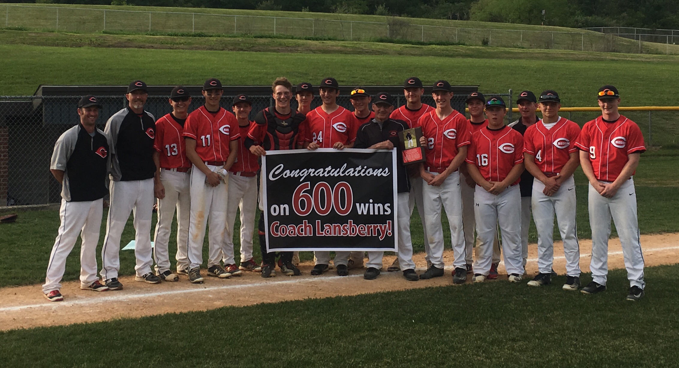 Players and coaches surround Sid Lansberry after he was presented a banner and plaque from the Clearfield Area Baseball Association for win No. 600.