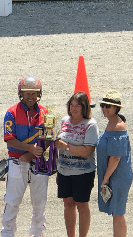 CHARLES "BUSTER" DISALVO TROPHY for the most driving wins at the Clearfield County Fair harness races is presented to Roger Hammer by Susan Roessner, center, and Caroline Castagnolo, nieces of DiSalvo. (Photo by Sue Kavelak)
