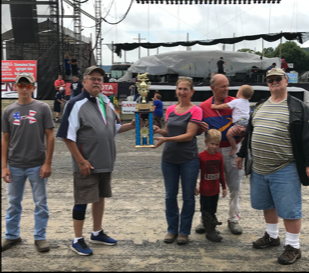 CHARLES "BUSTER" DISALVO TROPHY for driver with most wins in the Clearfield County Fair harness racing meet is accepted by Christine Schadel, whose husband Todd claimed with nine trips to Victory Lane. Presenters were Dave Semelsberger, second from left, and Jim Semelsberger, right, friends of the DiSalvo family. Todd's son Cody is on the left. Roger Hammer, a friend of the Schadel family, joined the celebration with two of his grandchildren. (Photo by Sue Kavelak)