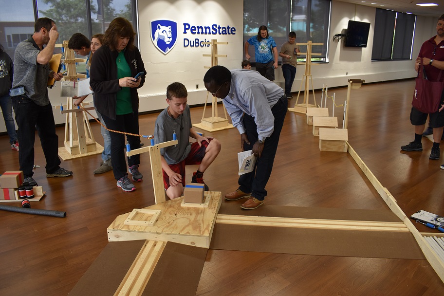 Assistant Professor of Engineering Daudi Waryoba, at center, explains to a student how robots will navigate a portion of the obstacle course for BEST Robotics 2019, during a preview of the course that teams received in the student union.  (Provided photo)