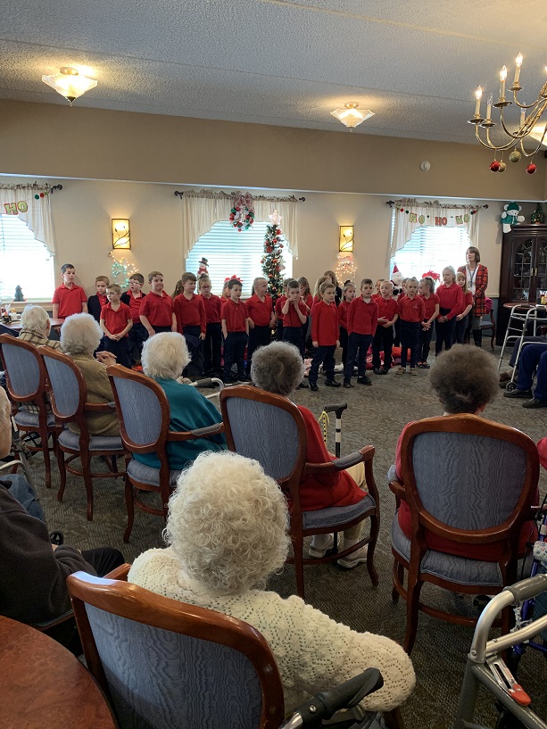 DuBois Central Catholic first graders brought gift bags of personal care items to residents in the Christ the King Manor Personal Care Unit.  Together, the residents and students enjoyed singing Christmas carols. (Provided photo)