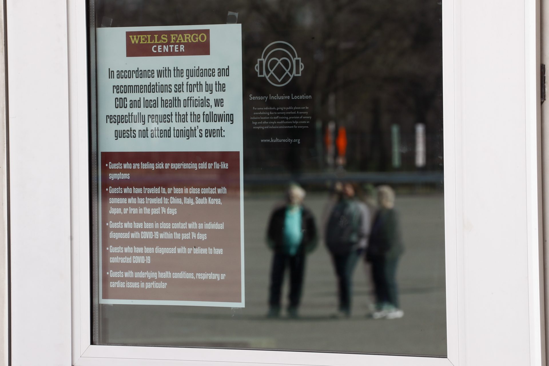 A health notice is posted on a glass door at the Wells Fargo Center, home of the Philadelphia Flyers NHL hockey team and the Philadelphia 76ers NBA basketball team, Saturday, March 14, 2020, in Philadelphia. All games at the Center have been postponed due to the COVID-19 pandemic. (AP Photo/Matt Slocum)