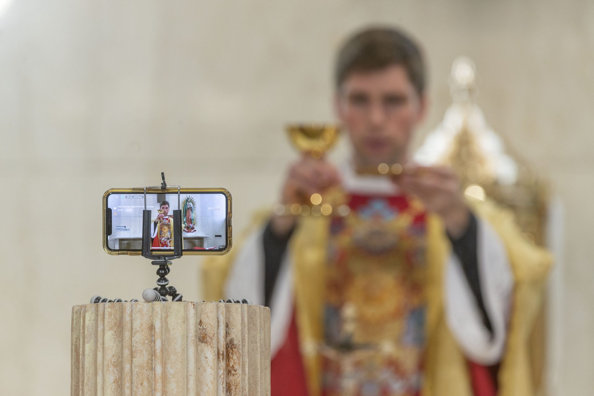 The Rev. Matthew Wheeler is seen on an iPhone screen live-streaming the celebration of the the Mass of the Lord's Supper at St. Anthony Parish in San Gabriel, Calif., Thursday, April 9, 2020. With no public Mass due to the coronavirus pandemic, the church live-streams its services.

 Damian Dovarganes / AP Photo