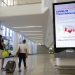 Arriving travelers walk by a sign in the baggage claim area of Terminal B at LaGuardia Airport, Thursday, June 25, 2020, in New York. New York, Connecticut and New Jersey are asking visitors from states with high coronavirus infection rates to quarantine for 14 days. The “travel advisory” affects three adjacent Northeastern states that managed to check the spread of the virus this spring as New York City became a hot spot. Travelers from mostly southern and southwestern states including Florida, Texas Arizona and Utah will be affected starting Thursday. The two-week quarantine will last two weeks from the time of last contact within the identified state. (AP Photo/Kathy Willens)