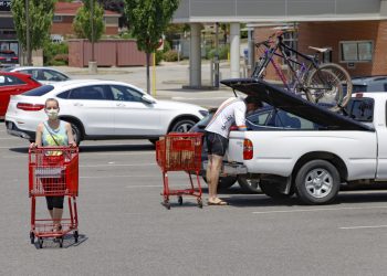 A woman and man wear COVID-19 protective masks as she pushes her shopping cart and a man loads his truck in a parking lot, Friday, July 3, 2020, in McCandless, Pa.  Keith Srakocic / AP Photo