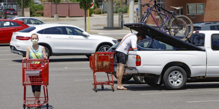 A woman and man wear COVID-19 protective masks as she pushes her shopping cart and a man loads his truck in a parking lot, Friday, July 3, 2020, in McCandless, Pa.  Keith Srakocic / AP Photo