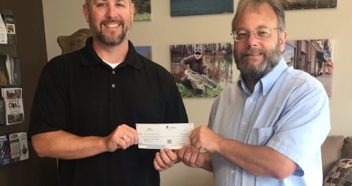 Visit Clearfield County Executive Director Josiah Jones presents a donation from proceeds of Lumberjack Chainsaw Carvers Event auction to Clearfield County Charitable Foundation Executive Director Mark McCracken. (Provided photo)