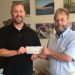 Visit Clearfield County Executive Director Josiah Jones presents a donation from proceeds of Lumberjack Chainsaw Carvers Event auction to Clearfield County Charitable Foundation Executive Director Mark McCracken. (Provided photo)