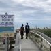 A sign in Myrtle Beach, S.C., Thursday, June 18, 2020, asks people to maintain social distancing on the beach. People are flocking to South Carolina's beaches for vacation after being cooped up by COVID-19 for months. But the virus is taking no vacation as the state has rocketed into the top five in the country in cases divided by population.   Jeffrey Collins / AP Photo