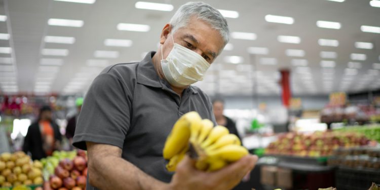 Senior man with disposable medical mask shopping in supermarket