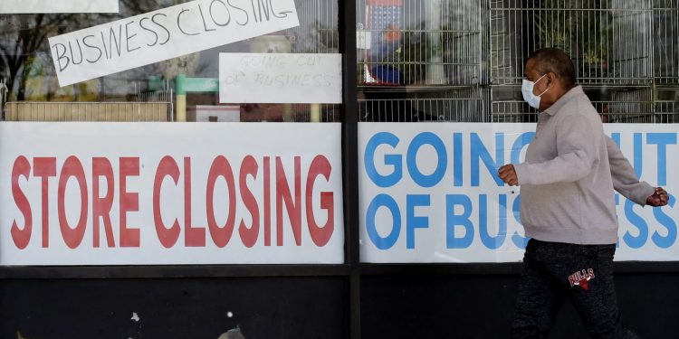 FILE - In this May 21, 2020 file photo, a man looks at signs of a closed store due to COVID-19 in Niles, Ill. U.S. businesses shed 2.76 million jobs in May, as the economic damage from the historically unrivaled coronavirus outbreak stretched into a third month. The payroll company ADP reported Wednesday that businesses have let go of a combined 22.6 million jobs since March.  Nam Y. Huh / AP Photo