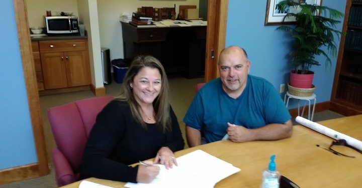 Danielle Parks, president of the MVEMS board of directors, and Wes Cartwright, one of the managers at MVEMS, sign the final paperwork to acquire 2.3 acres of land at the former Philipsburg Area Hospital Site, now the Philipsburg Area Commerce Park.  (Provided photo)