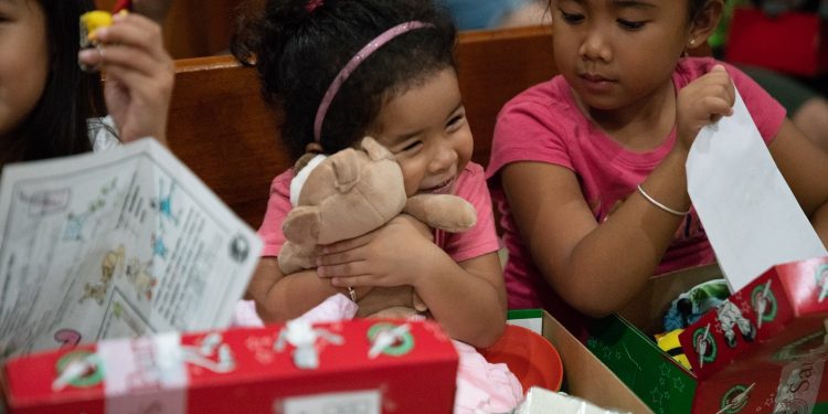 A girl in Saipan tenderly hugs the teddy bear she found in her shoebox gift.  (Photo is courtesy of Samaritan’s Purse)