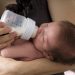 Close-up of mom bottle feeding a newborn baby.