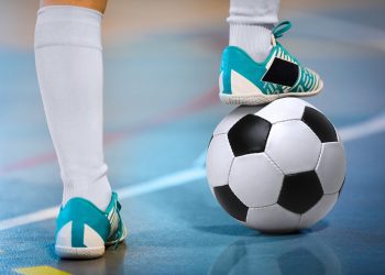 Indoor soccer sports player with ball. Football futsal player, ball, futsal floor. Sports background. Youth futsal league. Indoor football players with classic soccer ball.