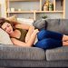 Shot of a young woman suffering from stomach cramps on the sofa at home