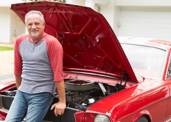 Retired Senior Man Working On Restored Classic Car Smiling To Camera