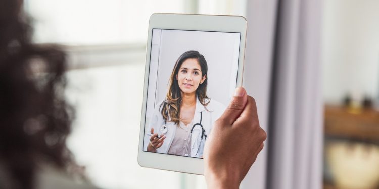 A female doctor offers an unrecognizable female patient advice during a telemedicine appointment.