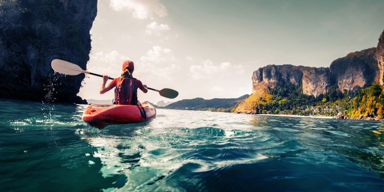 Lady paddling the kayak in the calm tropical bay