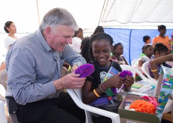 Franklin Graham encourages a girl in Belize as she explores the new items she found in her shoebox. (Photo courtesy of Samaritan’s Purse)