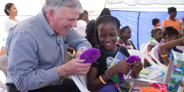 Franklin Graham encourages a girl in Belize as she explores the new items she found in her shoebox. (Photo courtesy of Samaritan’s Purse)