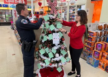 Clearfield Borough Assistant Police Chief Nathan Curry, and CCAAA Fundraising and Events Specialist Ronda Vaughn hang tags from a Giving Tree at the Family Dollar store in Clearfield. Curry and Vaughn head up the project for their respective agencies each year.