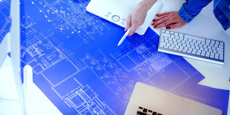 Two individuals reading and marking up a blueprint drawing.

Credit: Adobe Stock