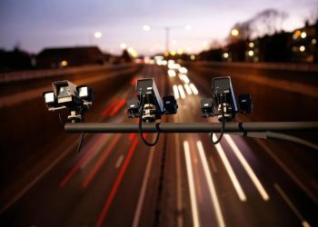 Speed camera monitoring busy traffic road at night.

Shutterstock