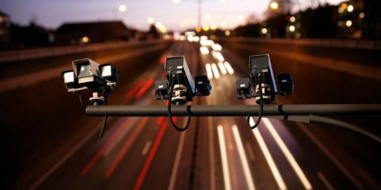 Speed camera monitoring busy traffic road at night.

Shutterstock