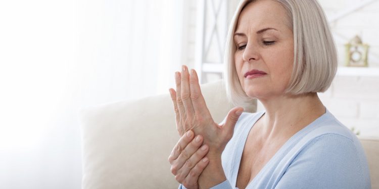 Woman massaging her arthritic hand and wrist closeup