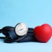 Blood pressure meter and toy heart on light blue background