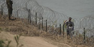 Migrant walks along concertina wire past a guardsman after crossing the Rio Grande from Mexico near the site where large buoys are being deployed to be used as a border barrier in Eagle Pass, Texas, Wednesday, July 12, 2023.

Eric Gay | AP Photo