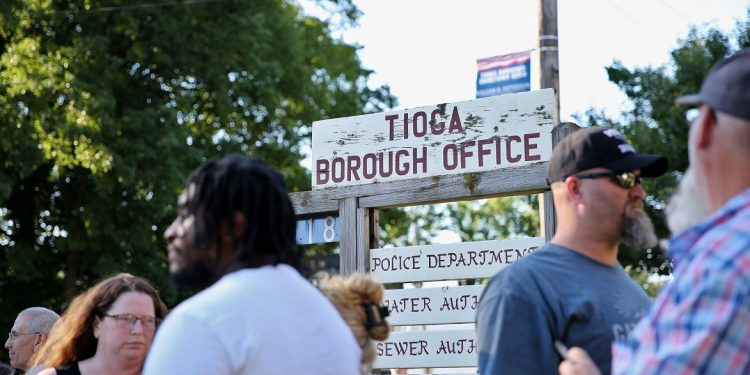 People stand in front of the sign for Tioga borough’s office.

Min Xian / Spotlight PA