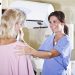 Woman, 50s, with nurse or technician, getting a mammogram.  Focus on nurse.