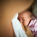 Close up of newborn baby girl being breastfed during her sleep.